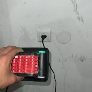 יד מחזיקה מטען עם סוללה מחוברת לשקע חשמל