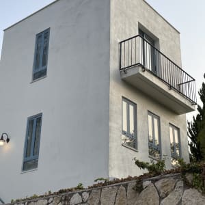 בניין לבן עם מרפסת וגדר אבן