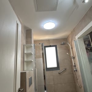 חדר אמבטיה עם מקלחת, שירותים ותאורה.