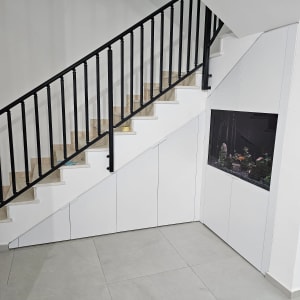 ארון עץ לבן מתחת למדרגות עם אקווריום מובנה