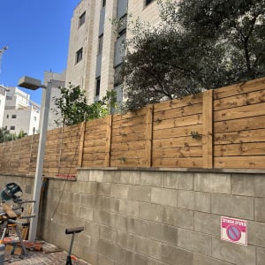 גדר עץ מותקנת ליד בניין עם כלי עבודה