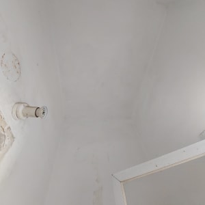 מנורה מותקנת על קיר לבן עם סימני תיקון