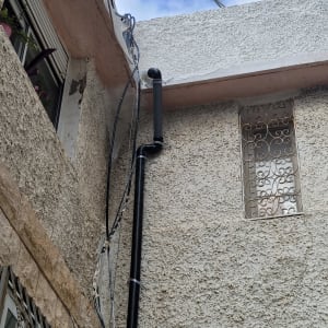 צינור שחור מותקן על קיר חיצוני של בניין