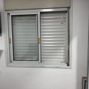 חלון עם תריסים בחדר, טלוויזיה על הקיר