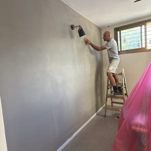 אדם צובע קיר בעזרת ספוג על סולם