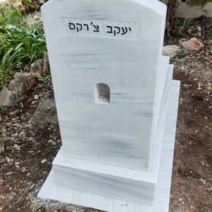 מצבה לבנה עם כיתוב בעברית בבית קברות
