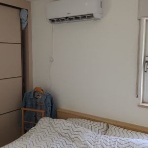 מזגן מותקן על קיר מעל מיטה בחדר שינה