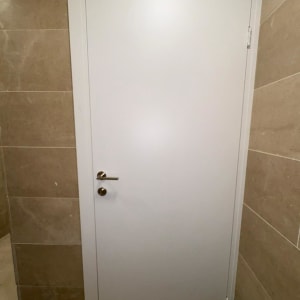 דלת לבנה עם ידית כסופה על רקע קיר חום