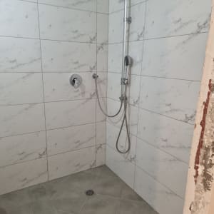 מקלחת חדשה עם אריחים לבנים וברז גשם