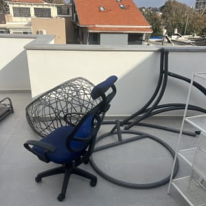 כיסא משרדי ומתקן מתכת על גג עם נוף עירוני