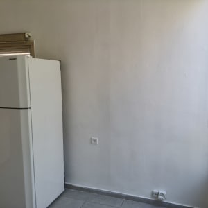 מטבח עם מקרר וקיר צבוע בלבן