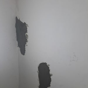 קיר עם תיקוני טיח כהים על רקע בהיר