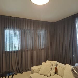 סלון עם וילונות כהים וספה בהירה