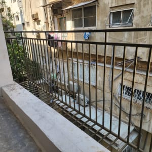 מעקה מתכת במרפסת עם מבנים ברקע