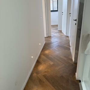 פרקט עץ בצורת זיגזג במסדרון מואר