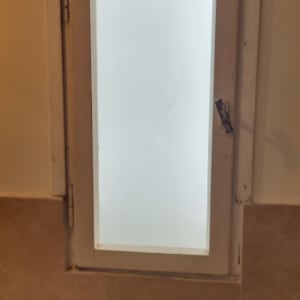 חלון עם זכוכית חלבית במסגרת עץ לבנה