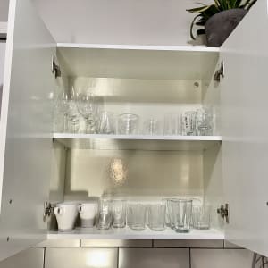 ארון מטבח פתוח עם כוסות זכוכית מסודרות על מדפים