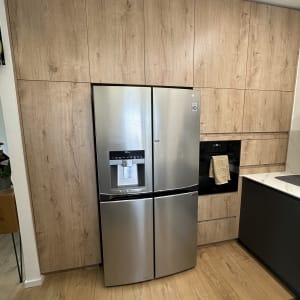 מקרר נירוסטה בין ארונות עץ במטבח מודרני