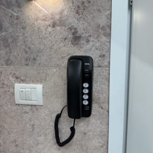 טלפון קווי מותקן על קיר עם מתגי חשמל