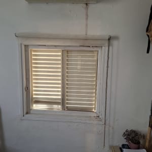 חלון עם תריסים סגורים וקיר לבן