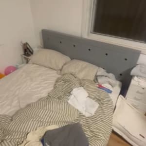 חדר שינה עם מיטה מבולגנת ומזוודה פתוחה