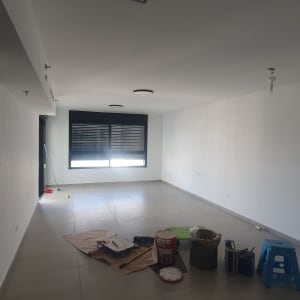 חדר עם ציוד לצביעה, כולל דלי צבע ומברשת.