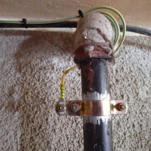 צינור חשמל עם חיבורי הארקה על קיר