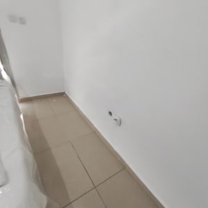 קיר לבן עם שקע חשמל ורצפת אריחים