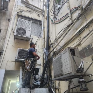 אדם עובד על צינורות חיצוניים בבניין ישן.