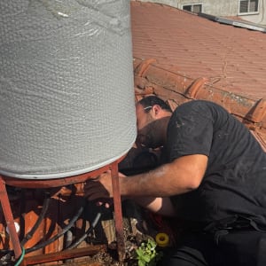 אדם עובד על דוד שמש על גג רעפים