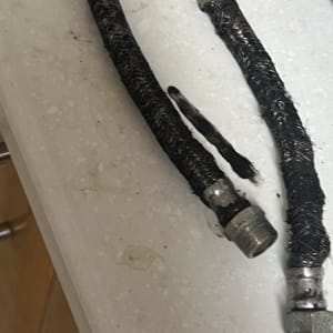 שני צינורות גומי עם חיבורים מתכתיים על משטח לבן