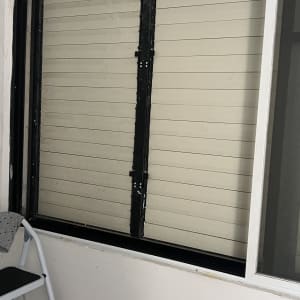 תריסים מותקנים על חלון עם סולם ליד