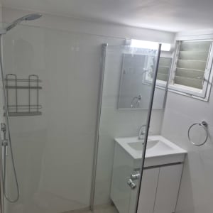 מקלחת עם דלת זכוכית וכיור לבן