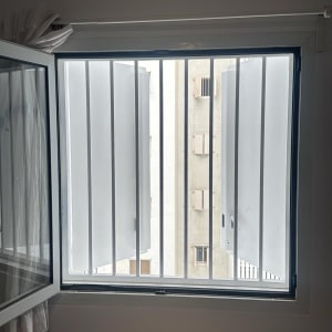 חלון עם סורגים פתוחים ומבנה חיצוני ברקע