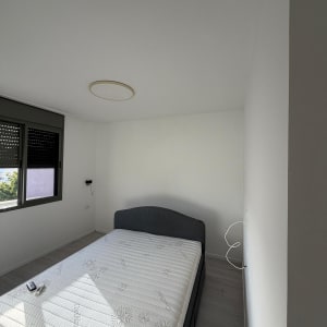 חדר שינה עם מיטה ומזרן, קירות לבנים