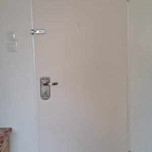 דלת לבנה עם ידית מתכת ובריח עליון