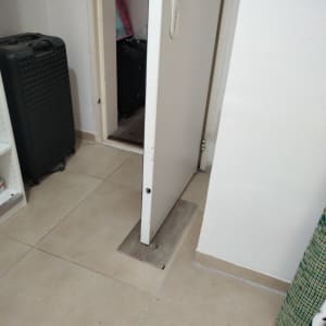 דלת לבנה פתוחה עם ידית לבנה על רצפה מרוצפת