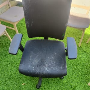 כיסא משרדי שחור עם כתמים על דשא ירוק