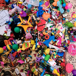 צעצועים מפוזרים על שטיח צבעוני, כולל כדורים, דמויות פלסטיק וכלי משחק.