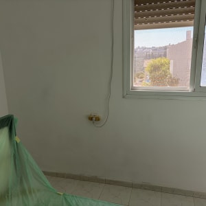 קיר צבוע עם חלון ויריעה ירוקה להגנה על הרצפה