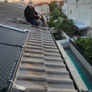 אדם עובד על גג רעפים עם כלים