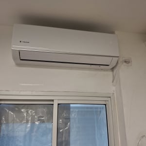 מזגן מותקן על קיר מעל חלון זכוכית