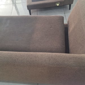 ניקוי ספה חומה עם מכונת ניקוי על רצפה אפורה