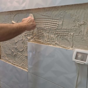 אדם מורח דבק על קיר להדבקת אריחים