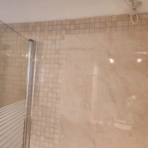 מקלחון זכוכית עם אריחי קרמיקה על הקיר