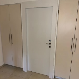דלת לבנה בין ארונות עם ידיות מתכת