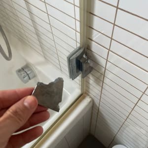 יד מחזיקה חלק מתכת שבור ליד דלת מקלחון