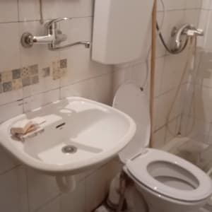 כיור ושירותים בחדר אמבטיה עם ברזים וצנרת