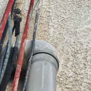 צינור אפור עם כבלים צבעוניים על קיר