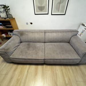 ספה אפורה עם כתמים על רצפת עץ